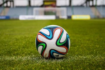 A vibrant adidas soccer ball on a green field, perfect for sports enthusiasts.